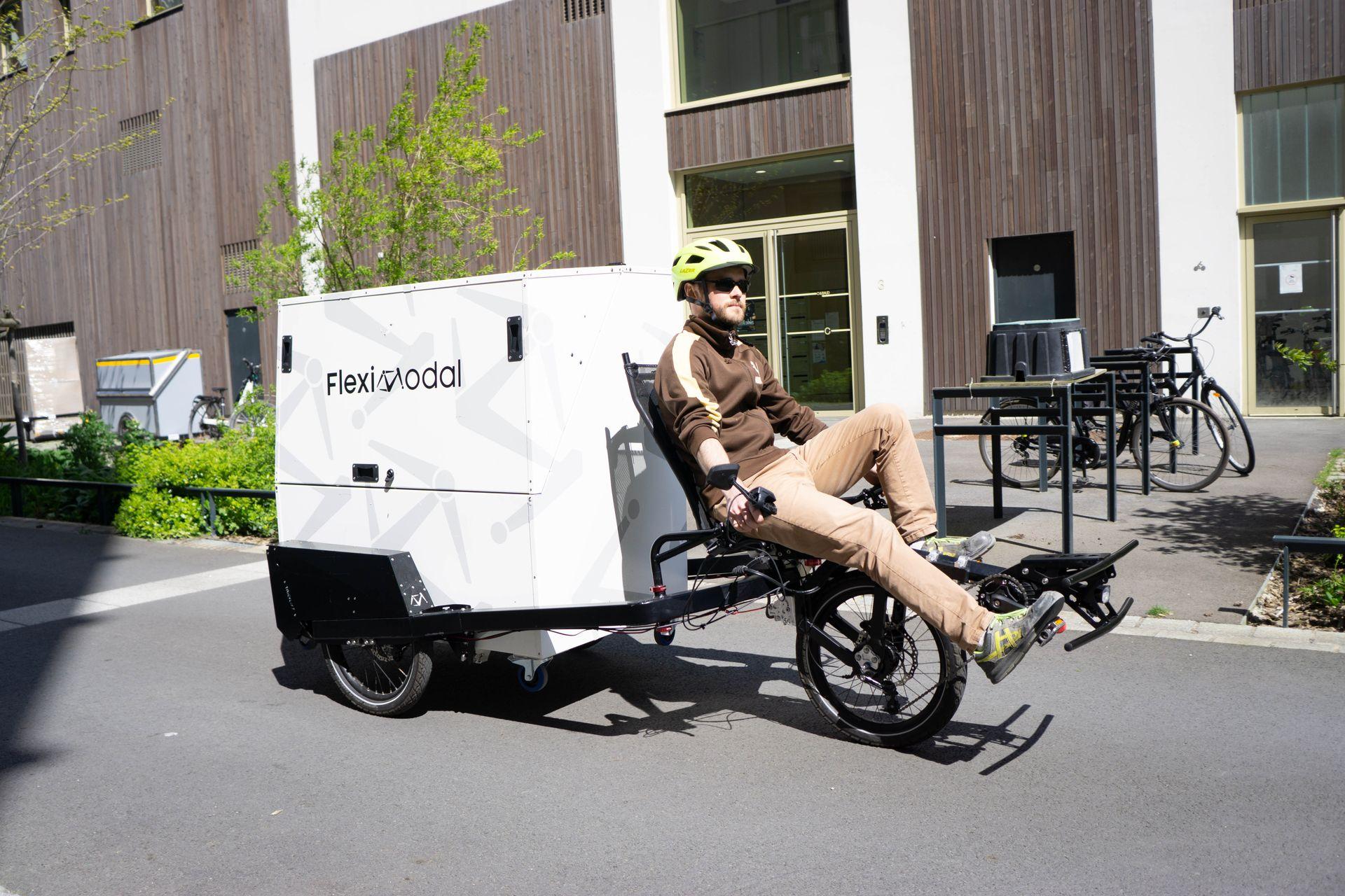 Triporteur TricyLift Personne conduisant un triporteur Tricylift équipé d'un caisson sécurisé pour la livraison de colis